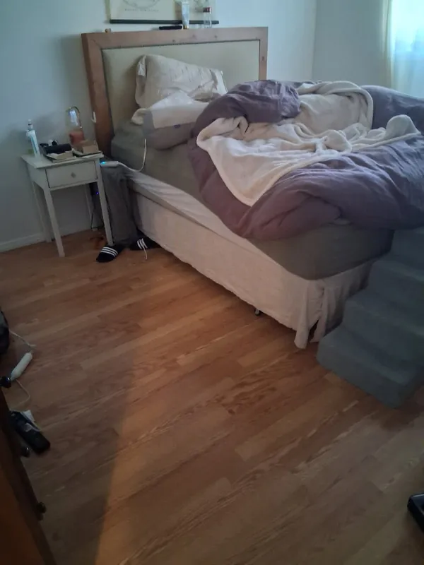 Bedroom with an unmade bed and items on the floor, before a deep cleaning in the Woodland Hills area