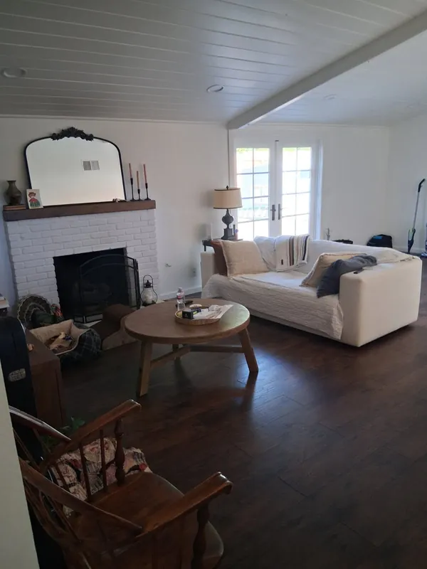 The living room with the sofa made up beside the white brick fireplace, after the deep cleaning