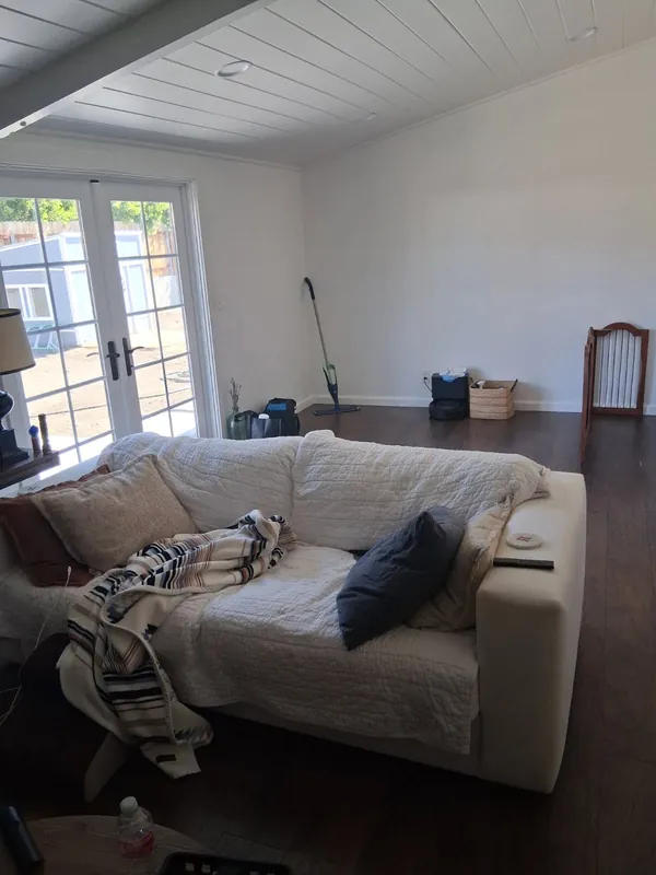 Living-room sofa with a tangled throw and a water bottle beside it, before a deep cleaning in the Woodland Hills area
