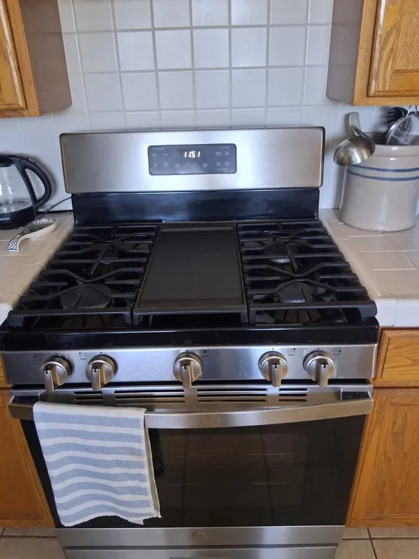 The same gas range wiped down, griddle and grates clear, after the deep cleaning