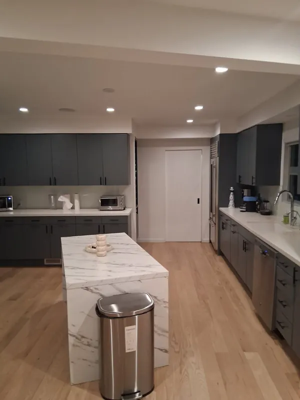 Kitchen with grey cabinets, white counters and a marble-look waterfall island after a regular cleaning in Beverly Hills