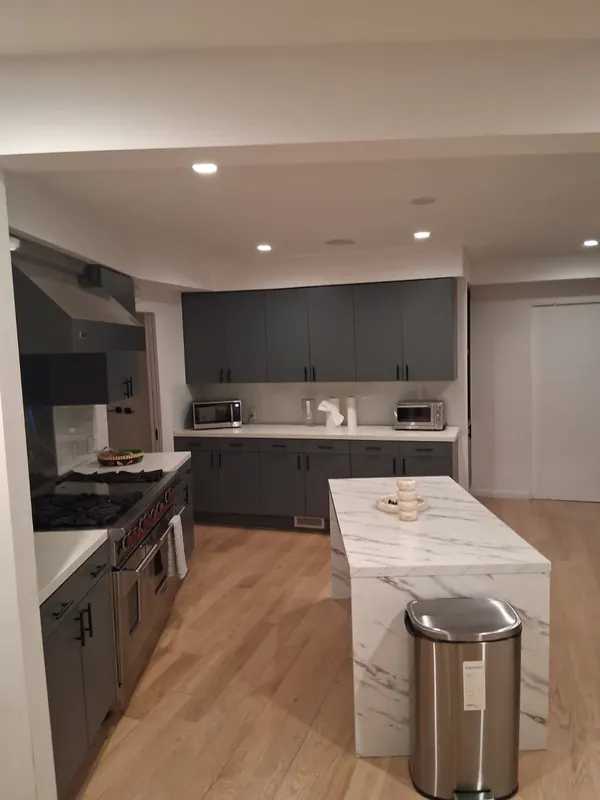 Kitchen with a stainless range, grey cabinets and a marble-look island after a regular cleaning in Beverly Hills